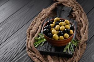 olives noires et vertes sur fond noir en bois foncé.