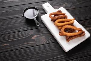 churros faits maison avec du chocolat sur un fond rustique en bois foncé. photo