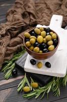 olives noires et vertes sur un fond rustique en bois foncé. photo