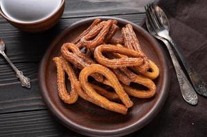 churros faits maison avec du chocolat sur un fond rustique en bois foncé. photo