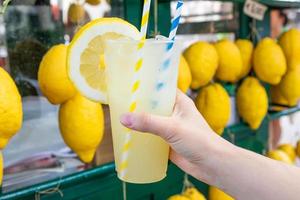 main caucasienne avec de la limonade fraîche et saine pendant l'été - fond de citrons photo