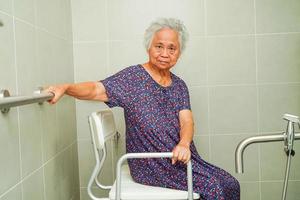 une vieille femme asiatique âgée utilise un rail de support de toilette dans la salle de bain, une barre d'appui de sécurité pour main courante, la sécurité dans l'hôpital de soins infirmiers. photo