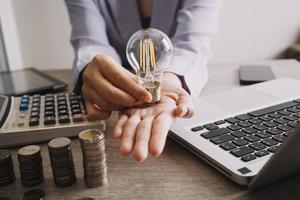 ampoule à économie d'énergie avec des piles de pièces de monnaie et un panier d'achat pour un concept d'économie, financier et commercial. photo