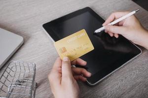 mains tenant une carte de crédit et utilisant un ordinateur portable. shopping en ligne photo