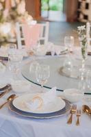 composition florale pour mariage d'été, faite de roses et de branches vertes sur une table de dîner au restaurant. , verre et assiettes dans le restaurant à l'extérieur par une journée venteuse avec effet de grain de film photo