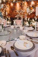 composition florale pour mariage d'été, faite de roses et de branches vertes sur une table de dîner au restaurant. , verre et assiettes dans le restaurant à l'extérieur par une journée venteuse avec effet de grain de film photo