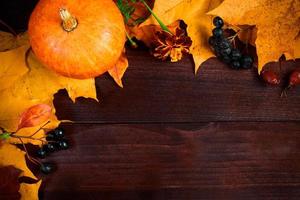 fond d'automne. cadre de citrouilles mûres et de feuilles tombées sur des planches de bois. concept de récolte et d'action de grâces. photo