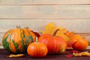 récolte d'automne. citrouilles mûres et feuilles tombées sur fond en bois. concept d'action de grâces et d'halloween. photo