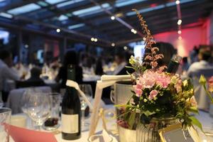 soirée avec des fleurs et des bouteilles de vin sur les tables photo