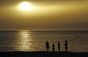 silhouette d'une famille pendant le coucher du soleil sur la côte à matala, crète photo