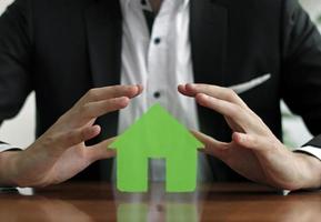 l'homme protège la maison de couleur verte avec les mains photo