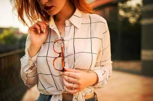 gros plan photo de lunettes tenant une femme rousse, porter un chemisier blanc.