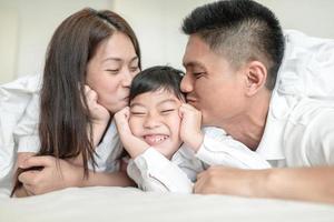 parents asiatiques embrassant leur petit fils sur les deux joues. photo