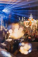 composition florale pour mariage d'été, faite de roses et de branches vertes sur une table de dîner au restaurant. , verre et assiettes dans le restaurant à l'extérieur par une journée venteuse avec effet de grain de film photo