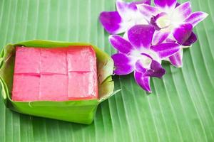 sorte de sucrerie thaïlandaise, gâteau sucré multicouche kanom chan sur feuille de bananier avec fleur d'orchidée photo