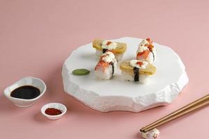 tamago et crabstick roll sushi sur plaque orientale blanche, fond rose.