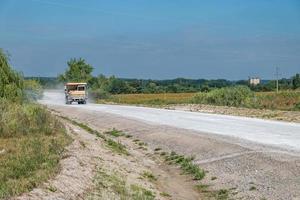 un gros camion à benne chargé de pierres roule sur une route poussiéreuse. industrie minière. matériel lourd. photo