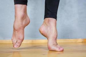 Pieds féminins pieds nus dans des leggings noirs sur un plancher en bois photo