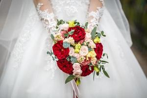 jeune fille mariée en séjour dans la rue de la ville et attend le marié avec bouquet de roses rouges et blanches photo