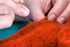 Artisan poussant un tissu feutré avec une aiguille en gros plan photo