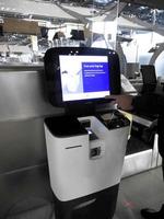 une main appuyant sur le moniteur, une machine d'enregistrement automatique à l'aéroport international de bangkok, le chargement des bagages, le dépôt des bagages en libre-service et l'obtention de la carte d'embarquement. photo