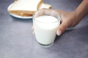 Choisissez à la main un verre de lait sur fond noir photo