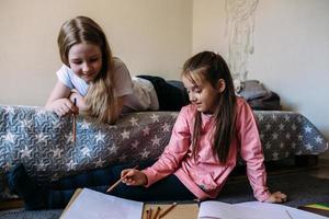 deux amies jouent à la maison, dessinent avec des crayons et des feutres et s'amusent photo