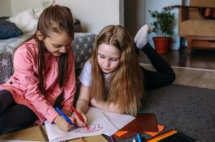 deux amies jouent à la maison, dessinent avec des crayons et des feutres et s'amusent photo