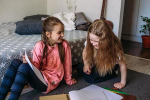 deux amies jouent à la maison, dessinent avec des crayons et des feutres et s'amusent photo