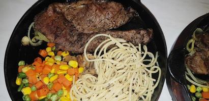 la meilleure nourriture du monde steak de boeuf accompagné de pommes de terre frites avec une délicieuse sauce aux champignons et une salade plaquée dans une belle assiette à rayures noires photo