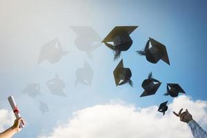 les mains des diplômés lancent des chapeaux de graduation. photo