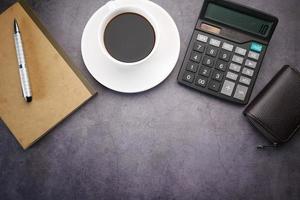 café de composition plate, bloc-notes et calculatrice sur fond noir. photo