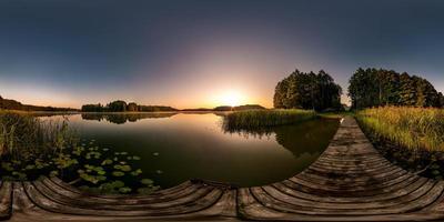 panorama hdri sphérique complet et harmonieux vue d'angle à 360 degrés sur la jetée en bois d'un immense lac ou d'une rivière le matin avec brouillard rose au lever du soleil en projection équirectangulaire, contenu vr photo