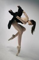 ballerine en body et veste noire improvise une chorégraphie classique et moderne dans un studio photo