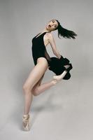 ballerine en body et veste noire improvise une chorégraphie classique et moderne dans un studio photo