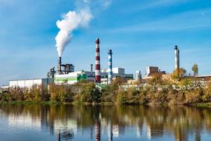 tuyaux de la scierie de l'usine de menuiserie près de la rivière. notion de pollution atmosphérique. paysage industriel pollution environnementale déchets de centrale thermique photo