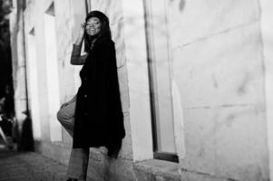 fille de mode afro-américaine en manteau et casquette de gavroche posée dans la rue. photo