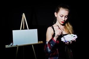 belle femme artiste peintre avec pinceaux et toile à l'huile posant en studio isolé sur noir. photo