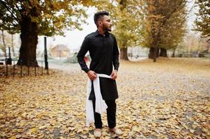 homme élégant indien en vêtements traditionnels noirs posés en plein air contre l'humeur d'automne. photo