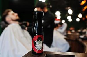 bel homme barbu au salon de coiffure, coiffeur au travail. vaporiser sur table. photo