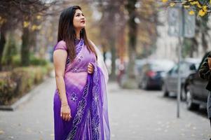 fille hindoue indienne au sari violet traditionnel posé dans la rue d'automne. photo