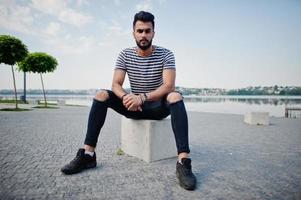 beau grand modèle d'homme à barbe arabe à chemise dépouillée posé à l'extérieur. mec arabe à la mode. photo