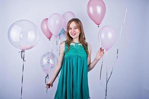 fille heureuse en robe turquoise verte avec des ballons colorés isolés sur blanc. célébrer le thème de l'anniversaire. photo