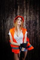 femme ingénieur en orange protège le casque et la veste de construction sur fond de bois. photo