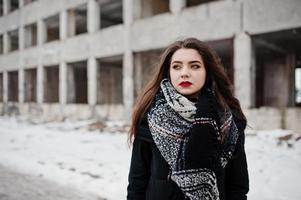 brune élégante fille décontractée en écharpe contre la place de l'usine abandonnée. photo