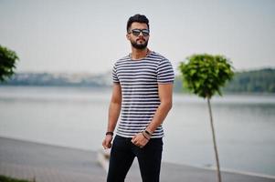 beau grand modèle d'homme à barbe arabe à chemise dépouillée posé à l'extérieur. mec arabe à la mode à lunettes de soleil. photo