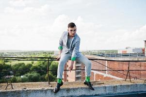 homme macho élégant rêveur en costume gris et lunettes posées sur le toit. photo