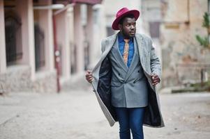 élégant modèle d'homme afro-américain en manteau gris, veste cravate et chapeau rouge. photo