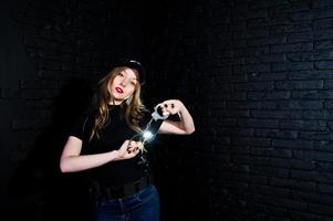 agent féminin du fbi en casquette et avec arme à feu au studio contre un mur de briques sombres. photo