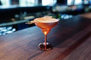 cocktail alcoolisé avec sucre fondu en verre bronze sur table de bar. photo